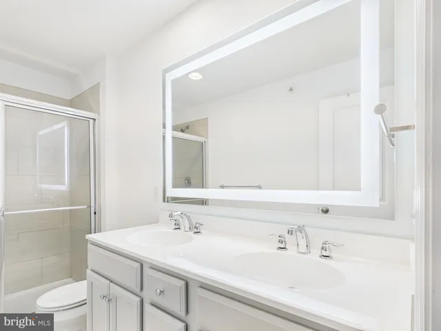 a bathroom with a sink toilet double vanity and shower