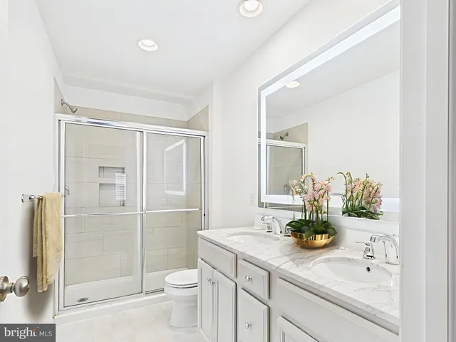 a bathroom with a granite countertop sink a toilet and shower