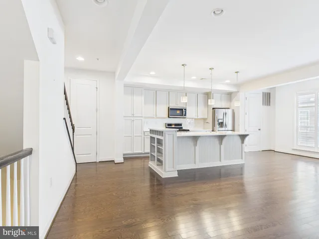 a large white kitchen with white cabinets and wooden floor