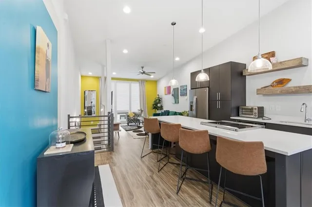 a kitchen with stainless steel appliances granite countertop a stove a sink dishwasher a dining table and chairs with wooden floor