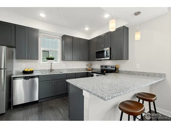 a kitchen with stainless steel appliances granite countertop a sink dishwasher a stove a refrigerator with a dining table and chairs