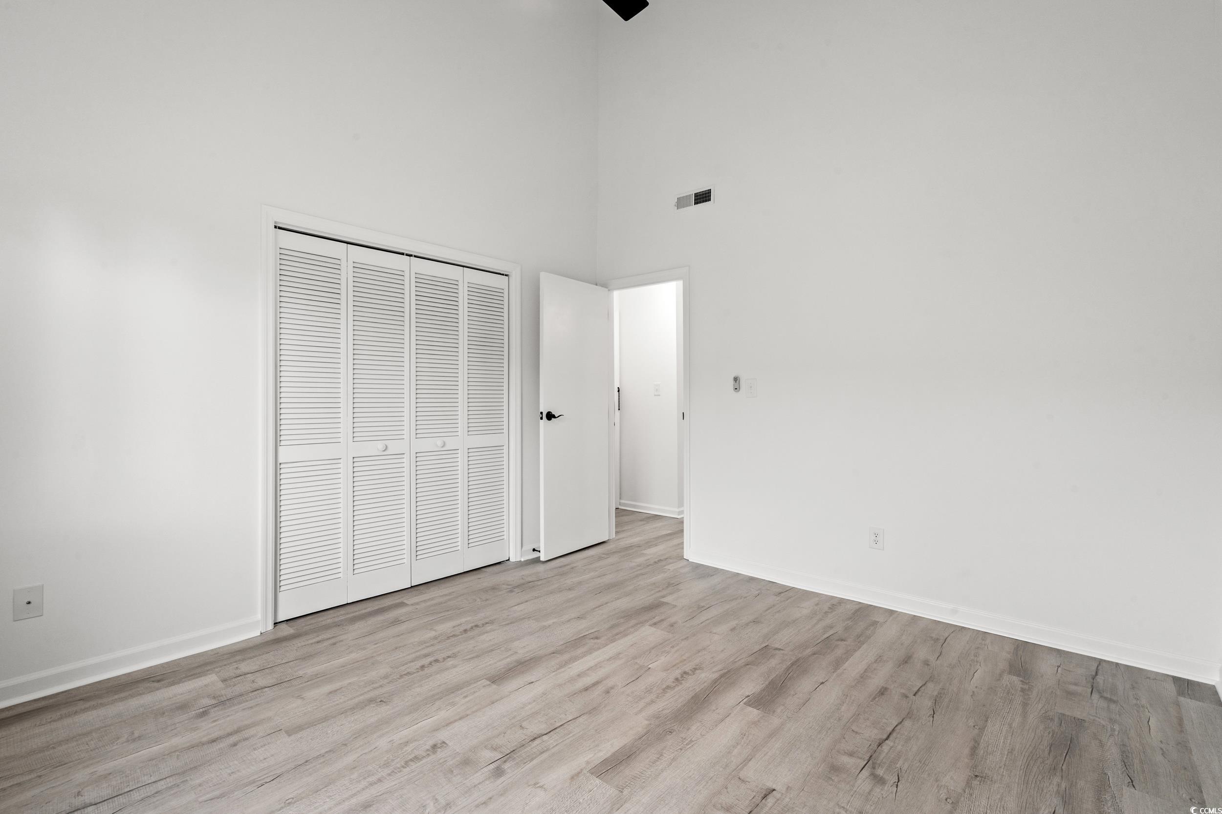 1890 Colony Drive, Unit 17L Surfside Beach, SC 29575 - Photo 20 of 38 Unfurnished bedroom with a towering ceiling, light wood finished floors, and a closet