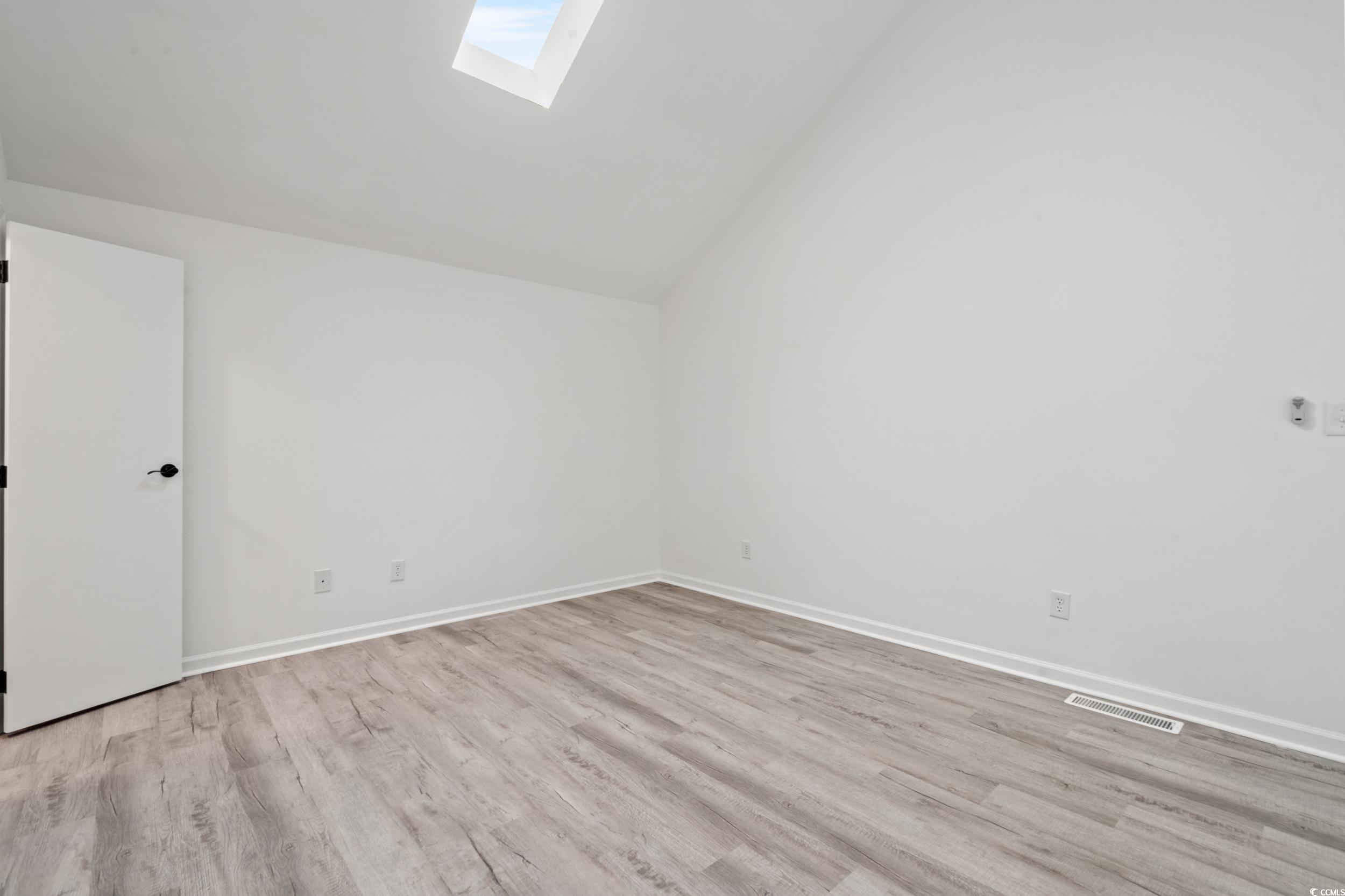 1890 Colony Drive, Unit 17L Surfside Beach, SC 29575 - Photo 25 of 38 Spare room with a skylight, vaulted ceiling, and light wood-style flooring