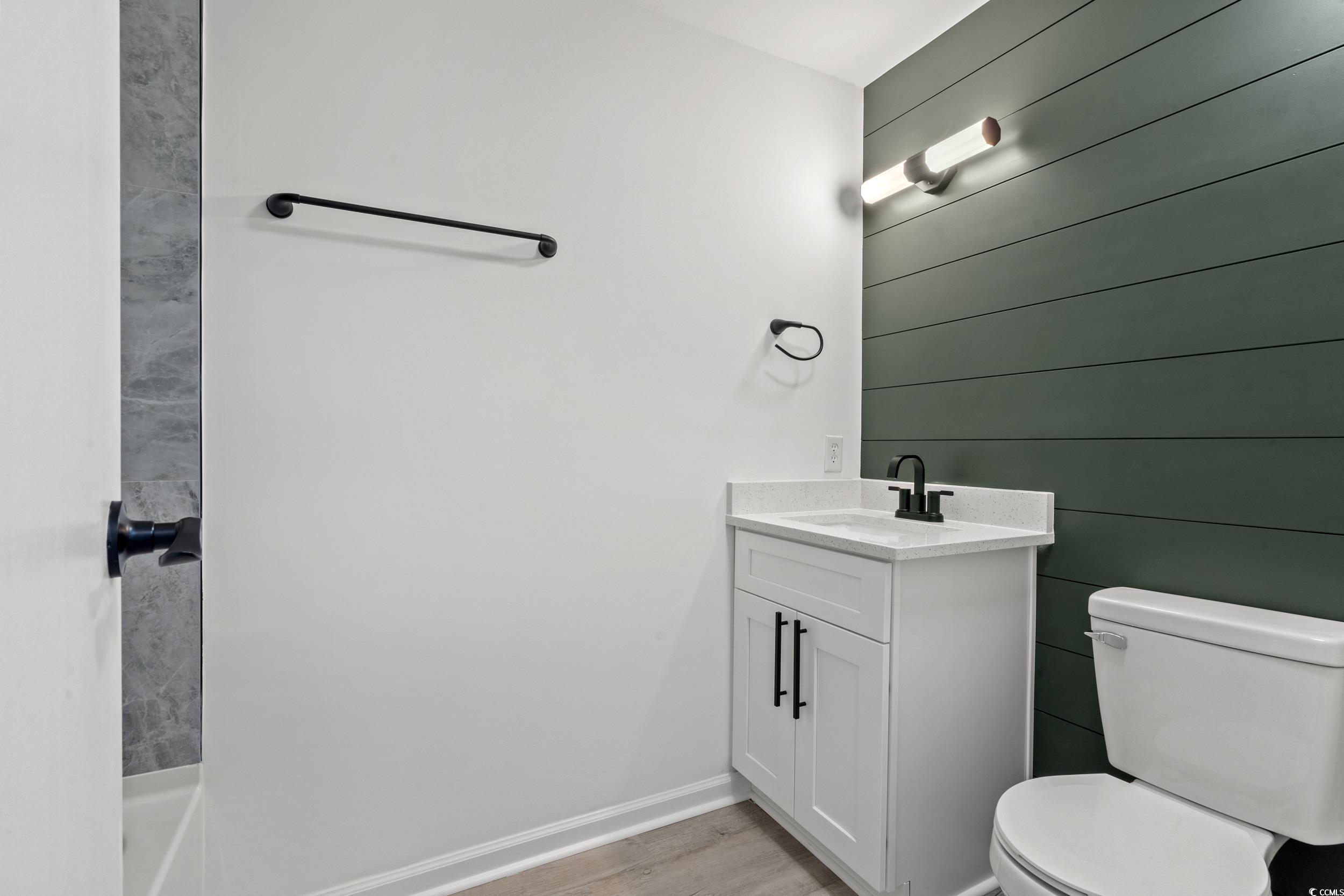 1890 Colony Drive, Unit 17L Surfside Beach, SC 29575 - Photo 26 of 38 Bathroom with vanity, light wood finished floors, and wood walls