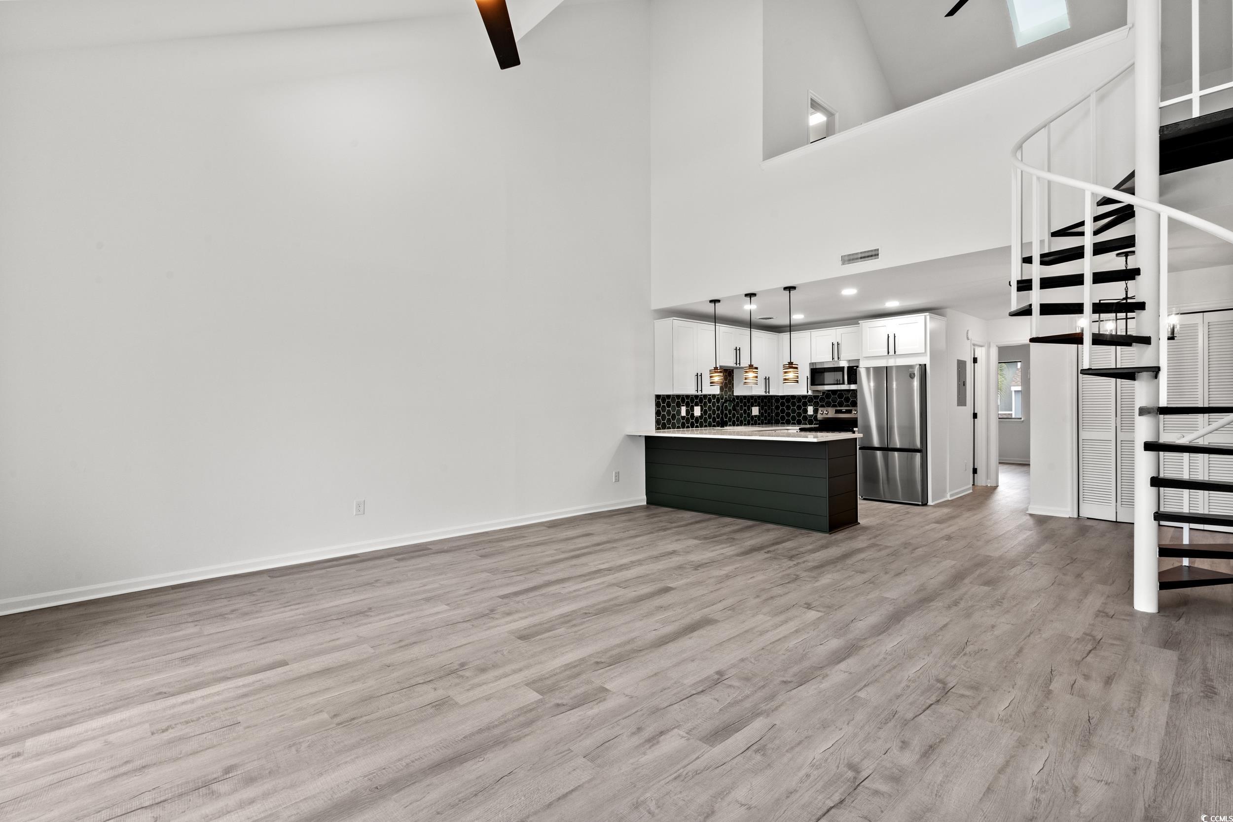 1890 Colony Drive, Unit 17L Surfside Beach, SC 29575 - Photo 7 of 38 Unfurnished living room featuring light wood finished floors, stairs, and high vaulted ceiling