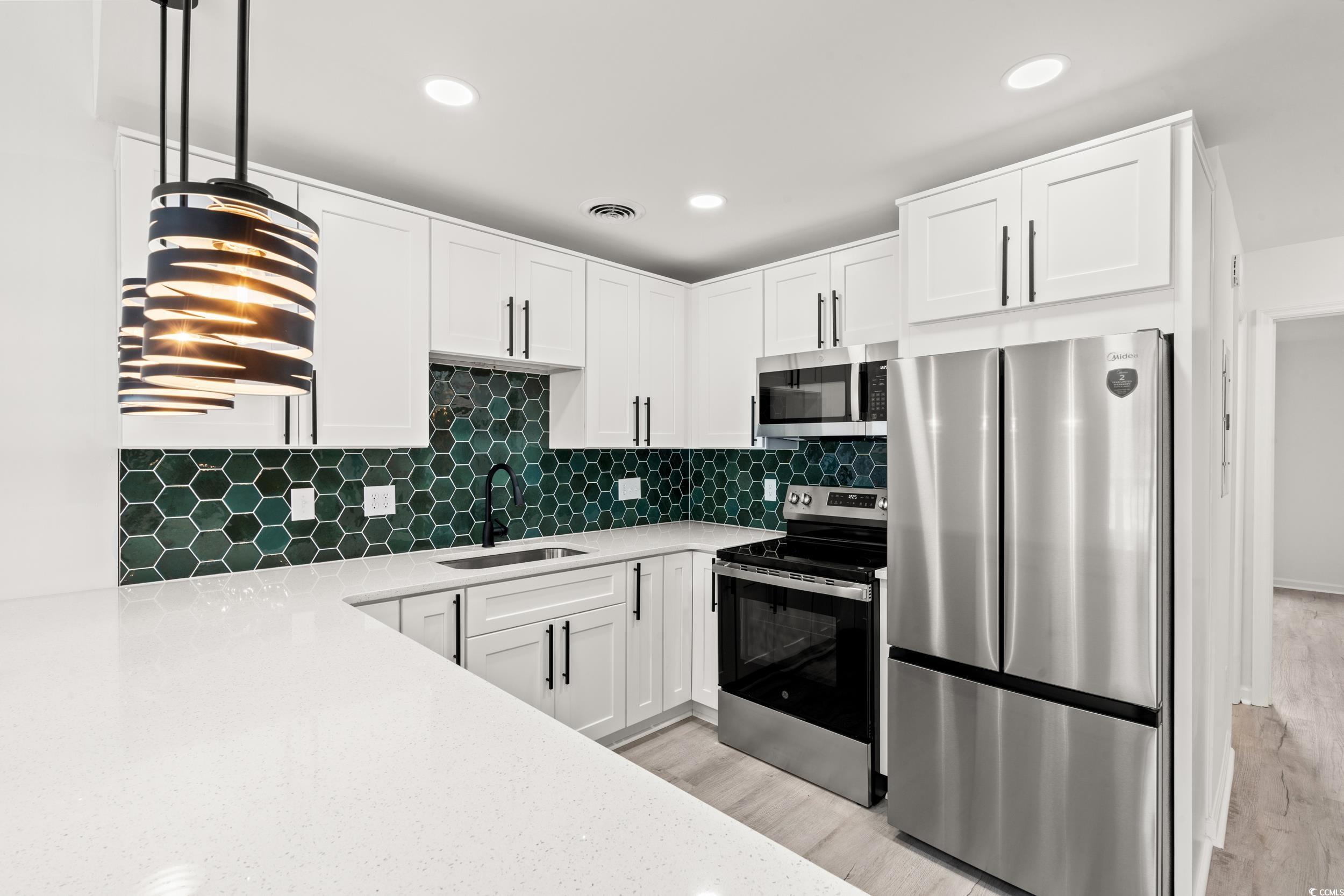 1890 Colony Drive, Unit 17L Surfside Beach, SC 29575 - Photo 8 of 38 Kitchen featuring stainless steel appliances, light stone countertops, white cabinets, pendant lighting, and backsplash