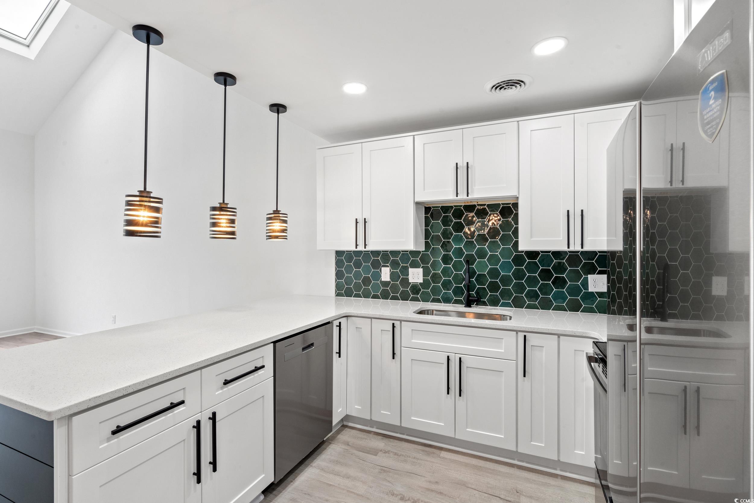 1890 Colony Drive, Unit 17L Surfside Beach, SC 29575 - Photo 10 of 38 Kitchen with a skylight, appliances with stainless steel finishes, light stone counters, decorative light fixtures, and tasteful backsplash
