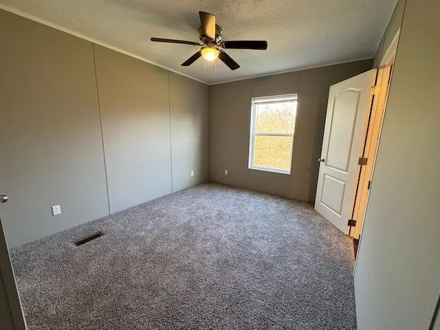 an empty room with windows and fan
