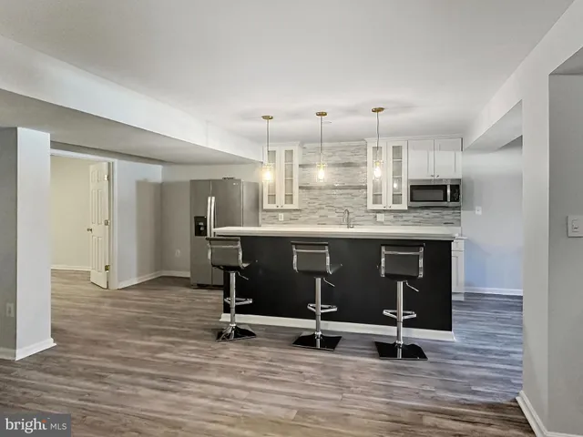 a kitchen with kitchen island stainless steel appliances a sink cabinets and wooden floor
