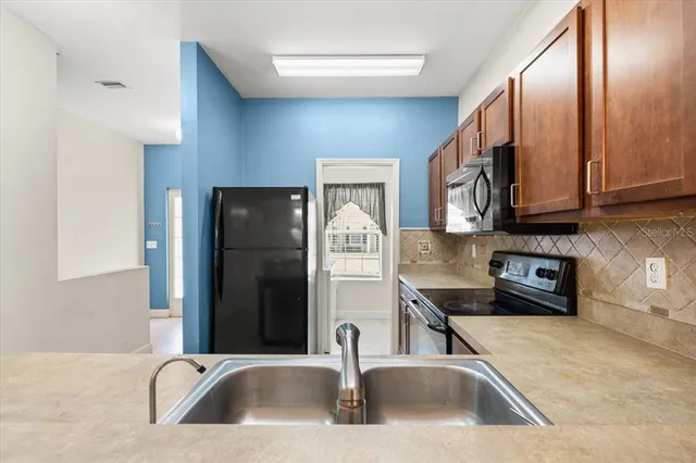 a kitchen with a sink a refrigerator and cabinets