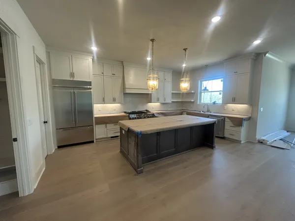 a large kitchen with a large counter top a sink stainless steel appliances and cabinets