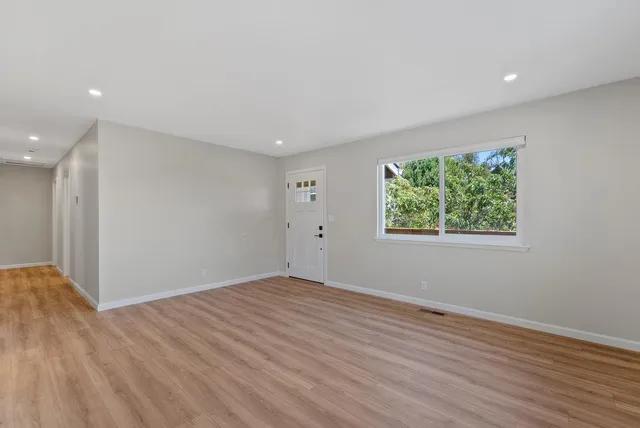 an empty room with wooden floor and windows