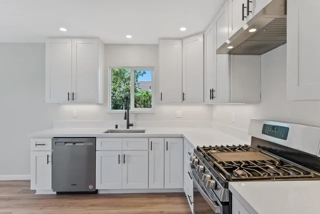a kitchen with white cabinets stove and sink