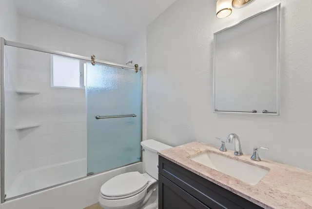 a bathroom with a granite countertop sink toilet a mirror and shower