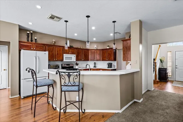 a kitchen with stainless steel appliances kitchen island a table chairs in it and wooden floors