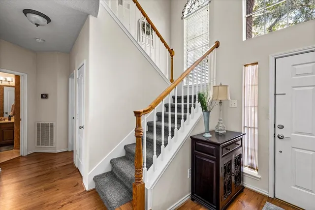 a view of staircase with lots of frames on wall and wooden floor