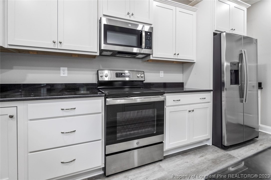 4750 Blue Sand Hill Road Fayetteville, NC 28312 - Photo 19 of 42 a kitchen with stainless steel appliances granite countertop white cabinets a stove a microwave and a refrigerator
