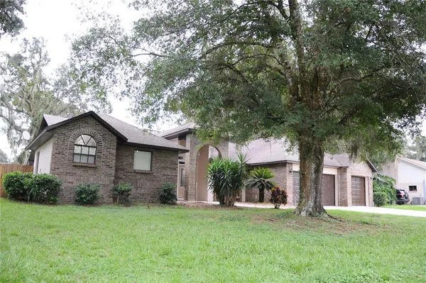 a front view of a house with a garden and tree