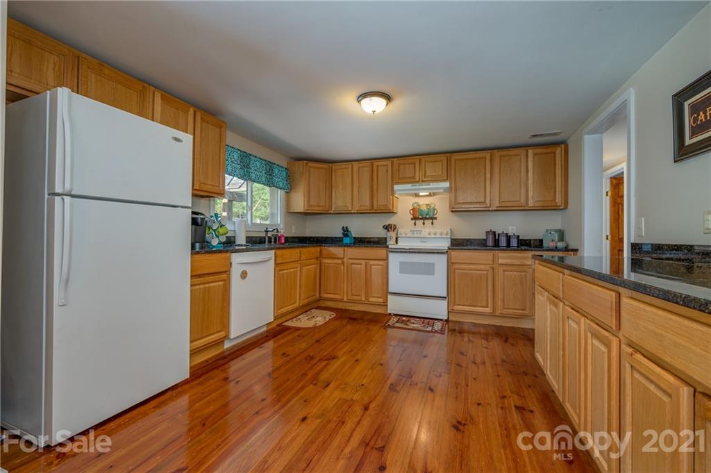 455 Sandy Plains Road Tryon, NC 28782 - Photo 11 of 28 a kitchen with granite countertop wooden floors a stove and a refrigerator