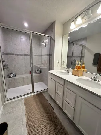 a bathroom with a sink a mirror a vanity and a glass door shower