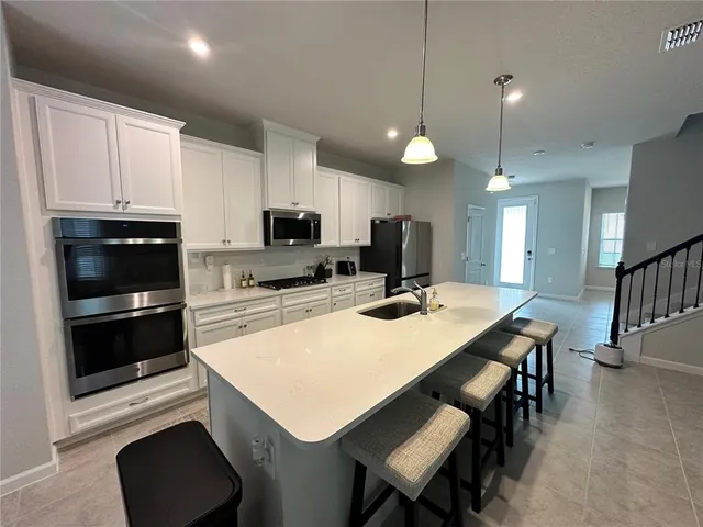 a kitchen with kitchen island white cabinets and stainless steel appliances