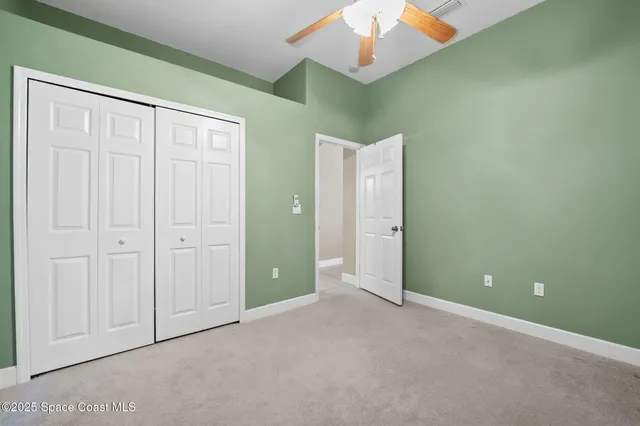 an empty room with wooden floor chandelier fan and windows