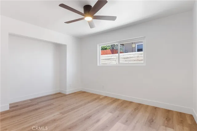 an empty room with a window and a fan