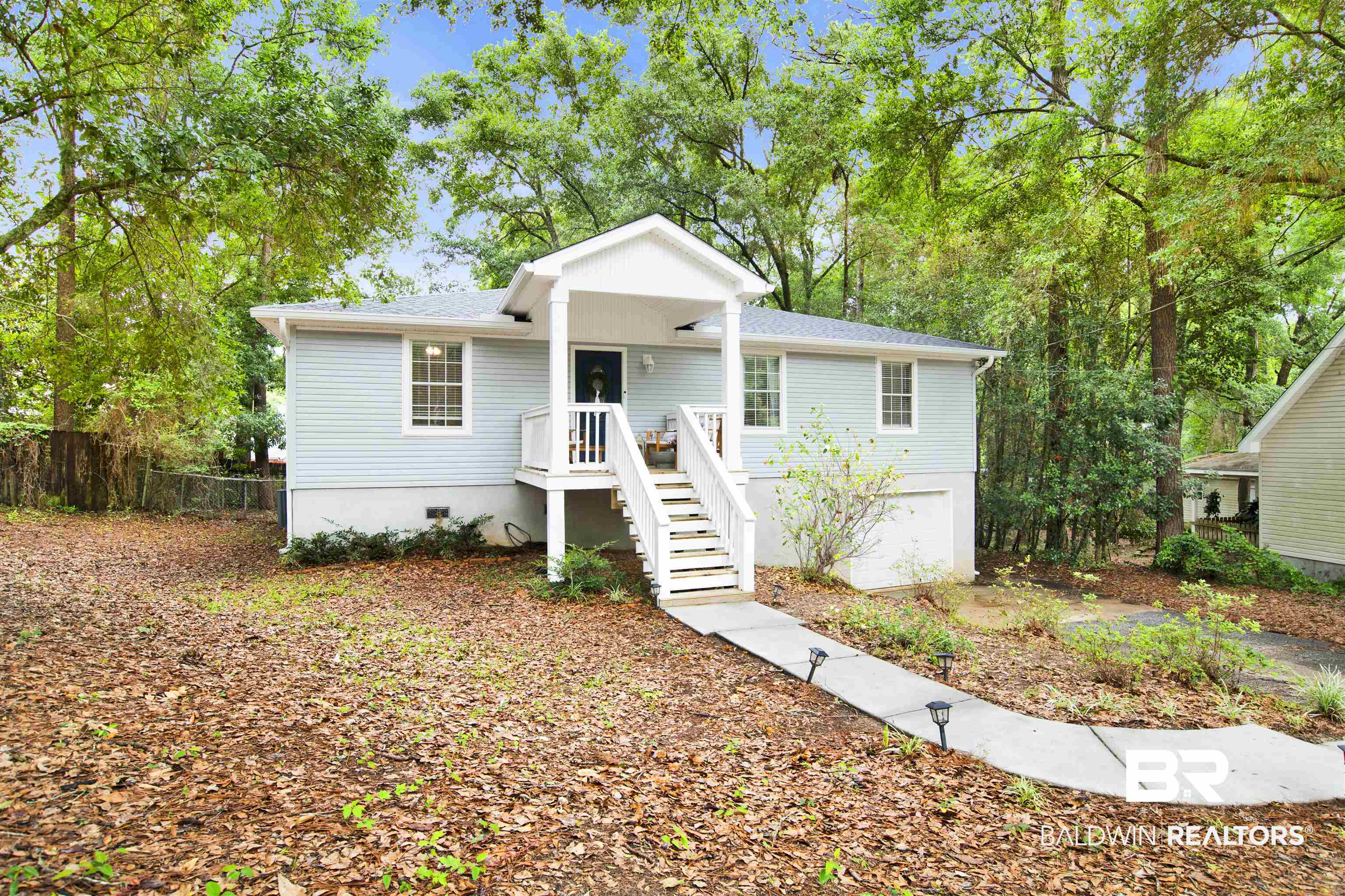 253 Maplewood Loop Daphne, AL 36526 - Photo 2 of 30 Light blue siding exterior featuring a white covered porch with railing and steps, white window trim, and a concrete pathway with small light fixtures