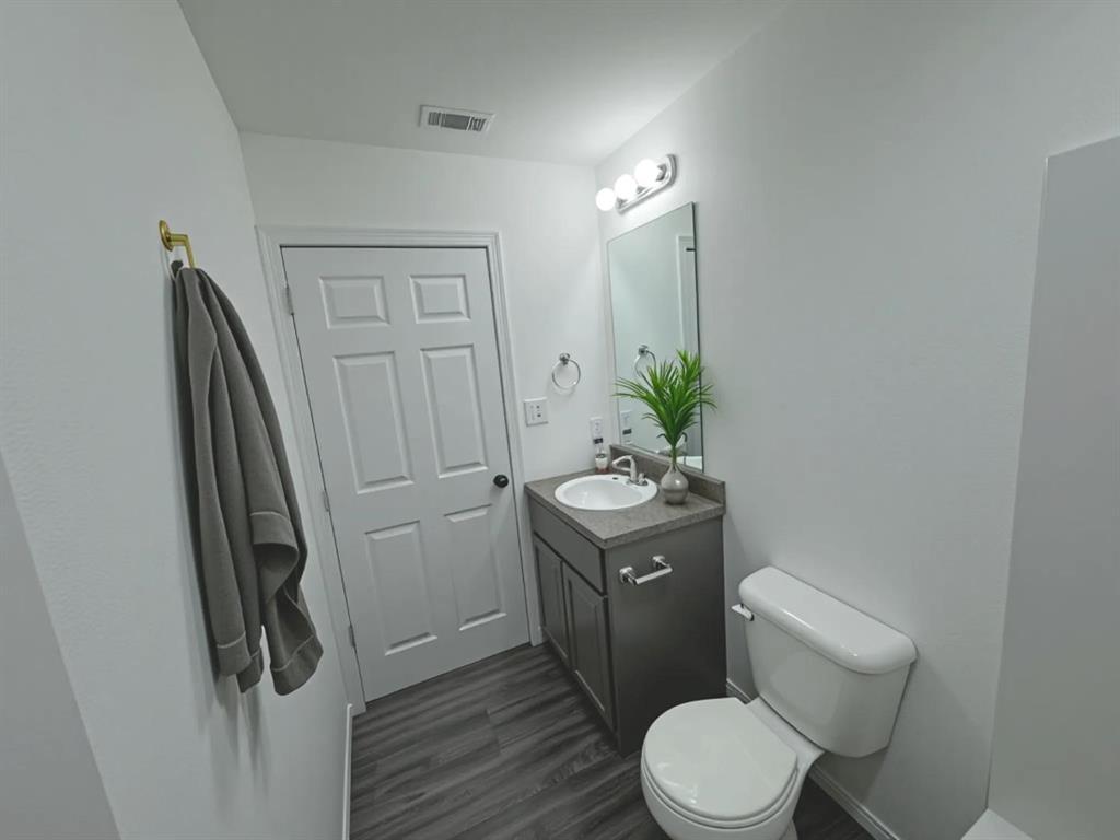 800 Sycamore Street Commerce, TX 75428 - Photo 7 of 8 a bathroom with a granite countertop toilet sink and mirror