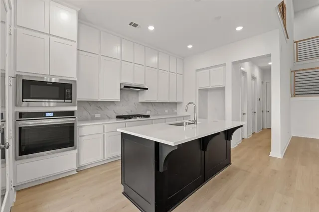 a kitchen with kitchen island granite countertop a sink appliances and cabinets