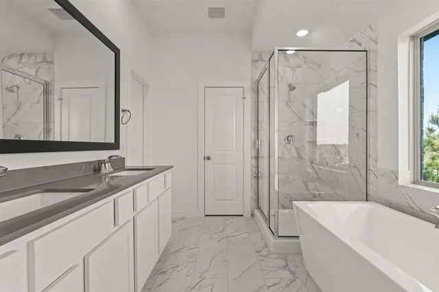 a bathroom with a granite countertop sink a mirror a bathtub and shower