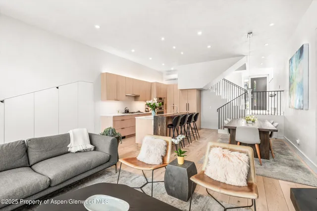 a living room with furniture kitchen view and a wooden floor