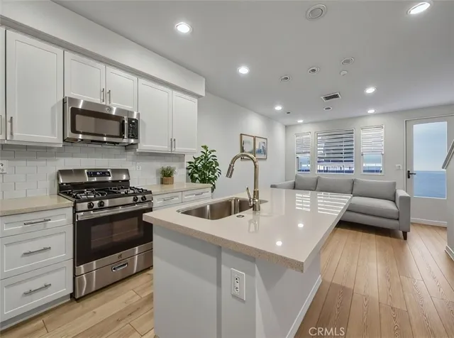 a kitchen with stainless steel appliances kitchen island granite countertop a sink a stove and a microwave
