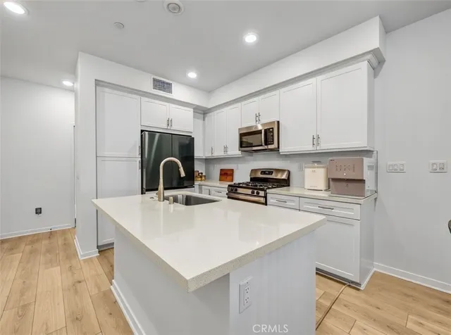 a kitchen with a sink a stove a microwave and white cabinets