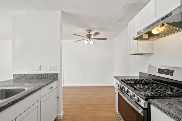 a kitchen with granite countertop a sink stove and cabinets