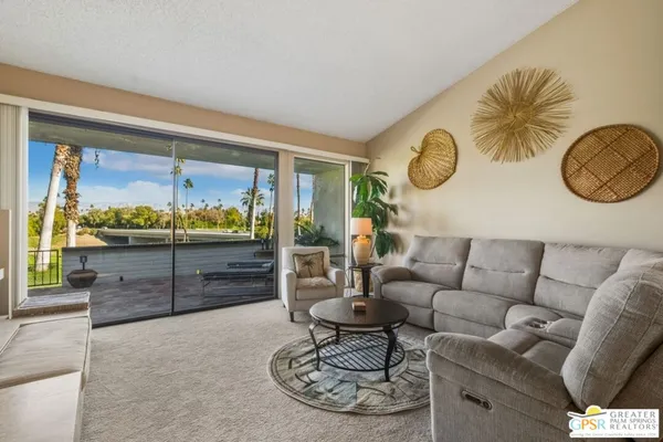 a living room with furniture a large window and wooden floor