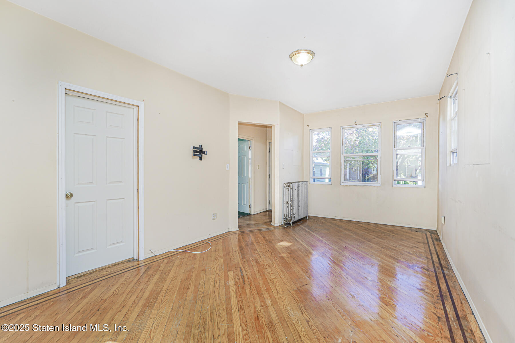 252 Dickie Avenue Staten Island, NY 10314 - Photo 11 of 37 a view of an empty room with window and wooden floor