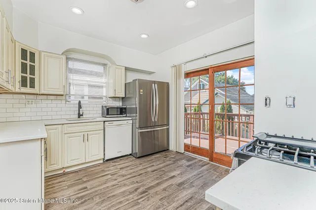 a kitchen with stainless steel appliances granite countertop a refrigerator a stove a sink dishwasher a dining table and with wooden floor