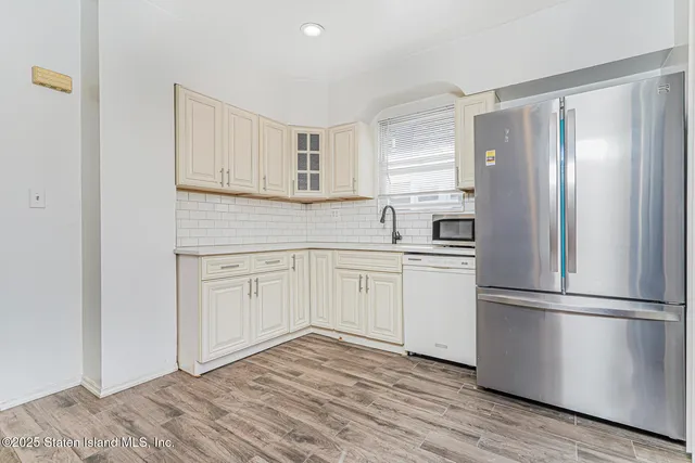 a kitchen with white cabinets white stainless steel appliances and wooden floors