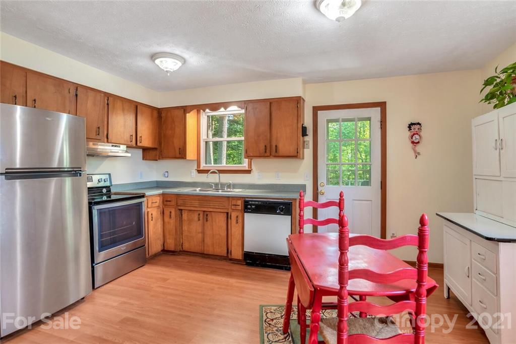 1158 Trammel Gap Road Saluda, NC 28773 - Photo 13 of 32 a kitchen with stainless steel appliances granite countertop a refrigerator sink and wooden cabinets
