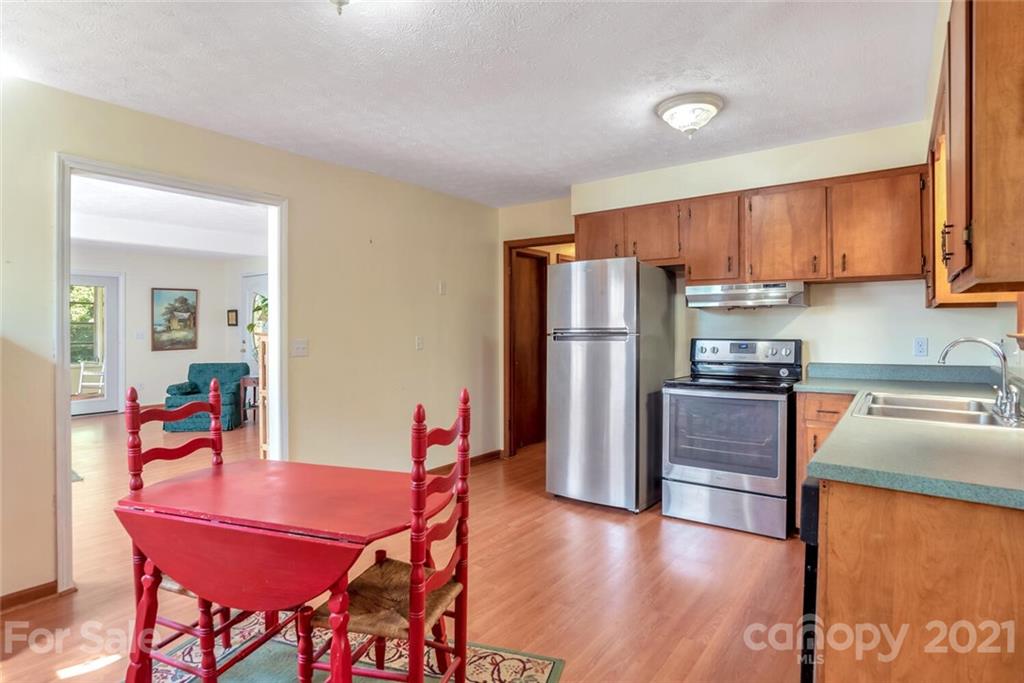 1158 Trammel Gap Road Saluda, NC 28773 - Photo 15 of 32 a kitchen with stainless steel appliances granite countertop a refrigerator a stove a sink a dining table and chairs with wooden floor