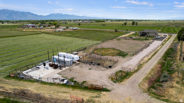 5702 950 North Ogden, UT 84404 - Photo 9 of 36 Expansive rural property featuring a multi-level residence with an attached garage, a circular fenced animal enclosure, a large gravel driveway, and surrounding agricultural fields