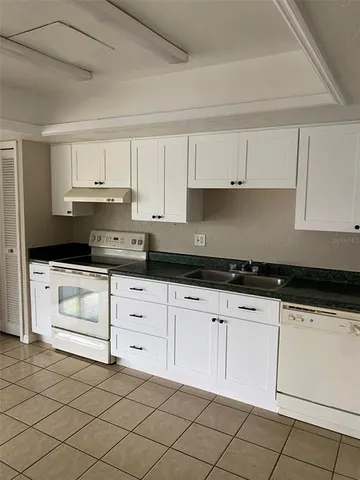 a kitchen with granite countertop white cabinets and white appliances