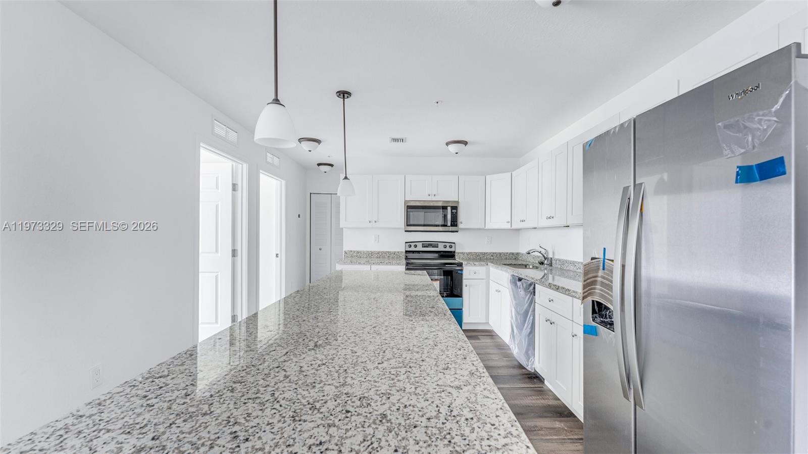 13375 Southwest 250th Street, Unit 104 Homestead, FL 33032 - Photo 17 of 27 a large kitchen with stainless steel appliances kitchen island a refrigerator sink and cabinets