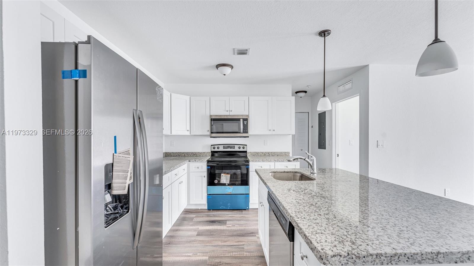 13375 Southwest 250th Street, Unit 104 Homestead, FL 33032 - Photo 19 of 27 a kitchen with stainless steel appliances granite countertop a refrigerator a oven and white cabinets