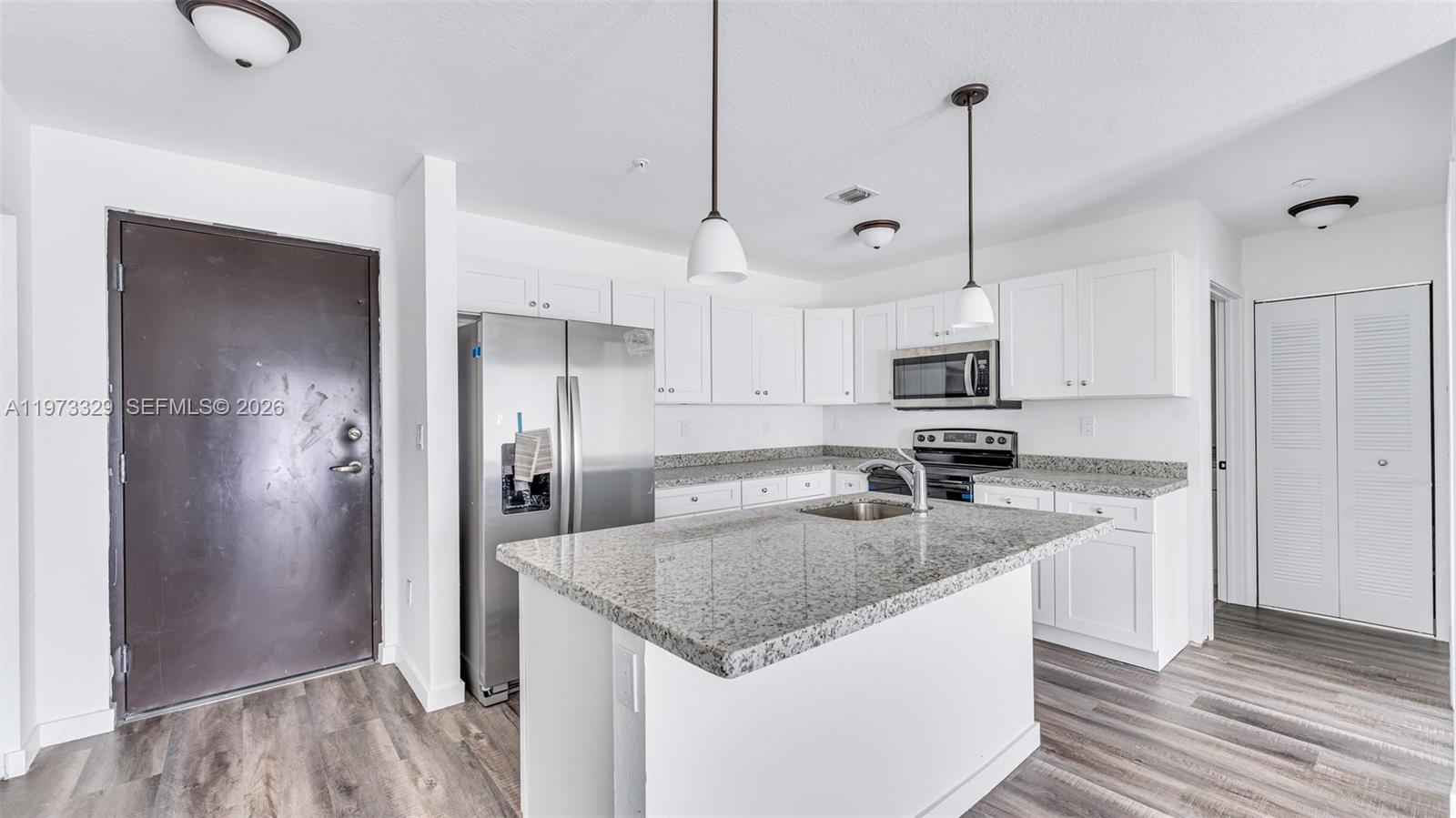 13375 Southwest 250th Street, Unit 104 Homestead, FL 33032 - Photo 20 of 27 a kitchen with stainless steel appliances granite countertop a refrigerator a sink a stove and a wooden floors