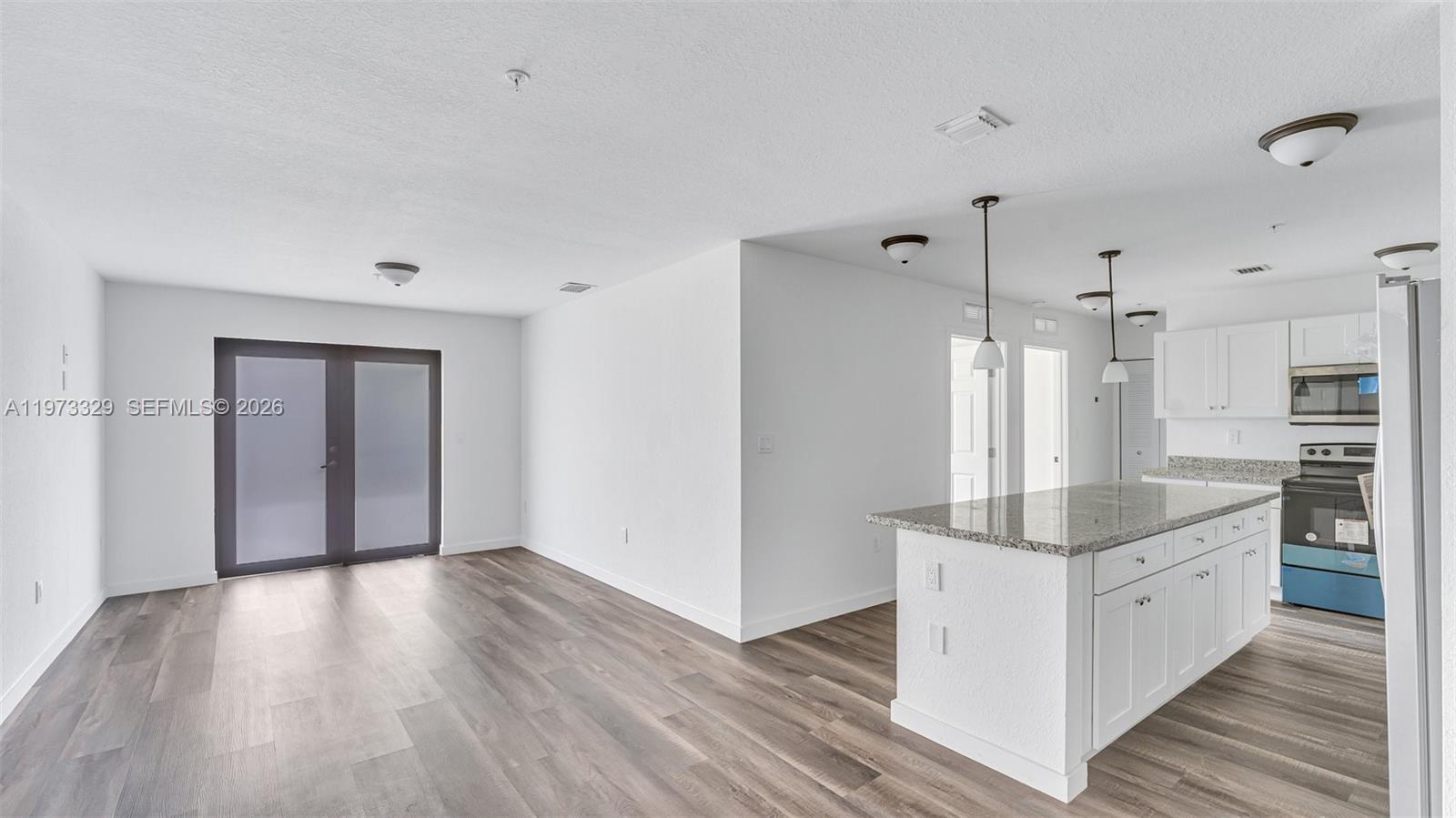 13375 Southwest 250th Street, Unit 104 Homestead, FL 33032 - Photo 2 of 27 a large white kitchen with wooden floor