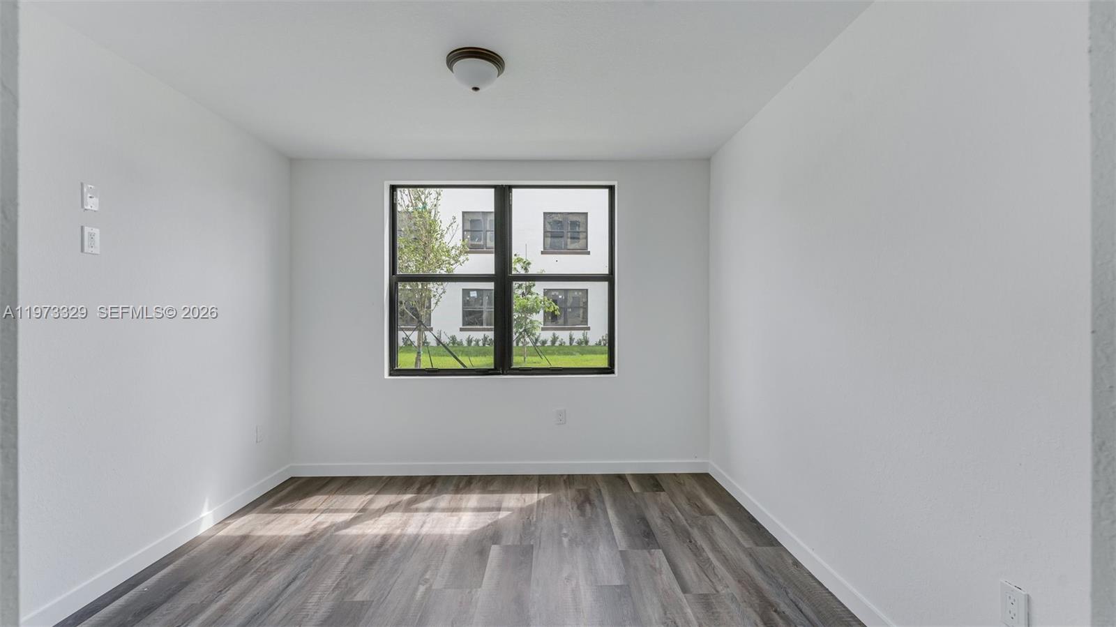 13375 Southwest 250th Street, Unit 104 Homestead, FL 33032 - Photo 26 of 27 a view of an empty room with wooden floor and a window