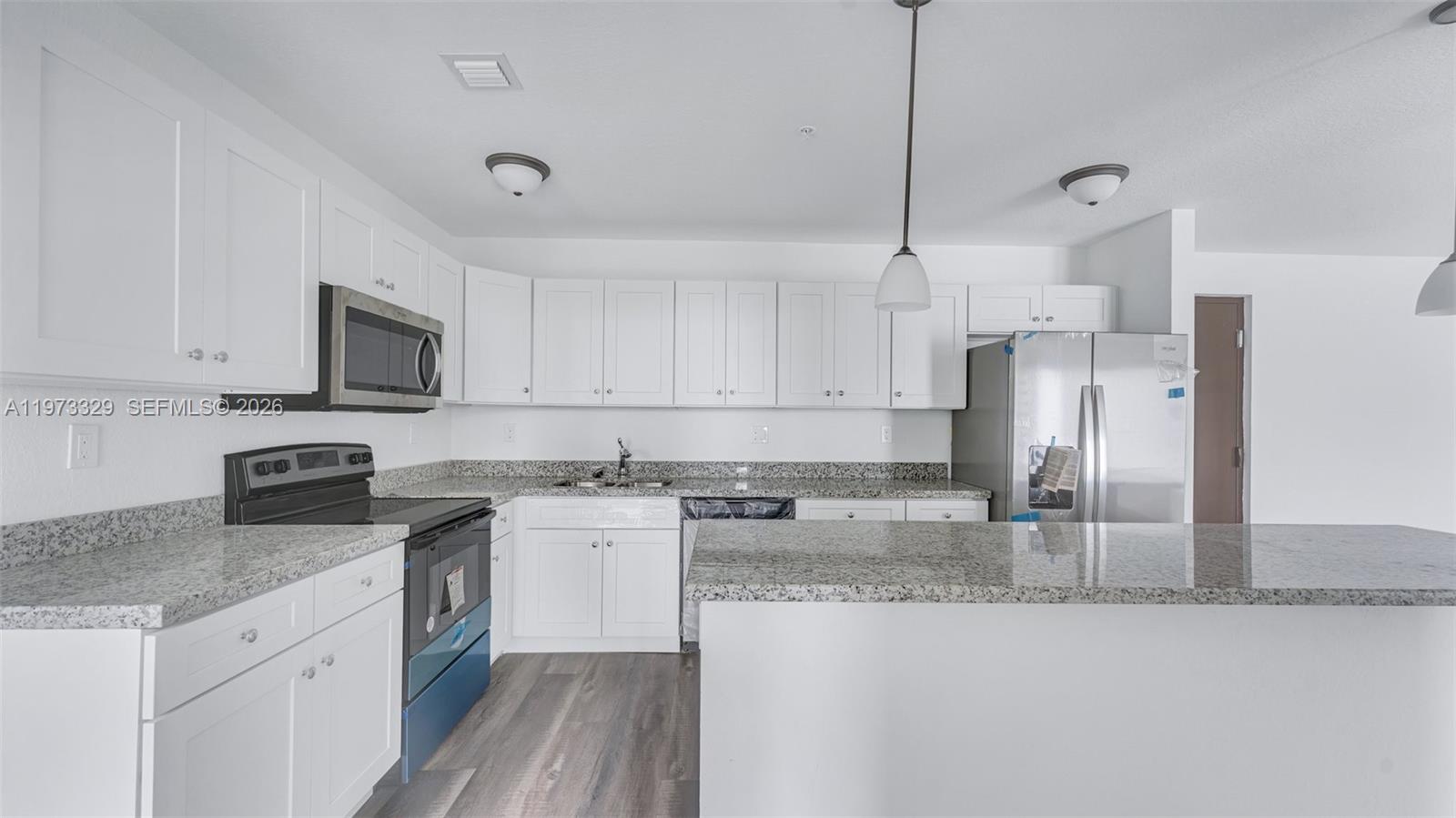 13375 Southwest 250th Street, Unit 104 Homestead, FL 33032 - Photo 9 of 27 a kitchen with stainless steel appliances granite countertop a sink a stove a refrigerator a microwave oven with white cabinets