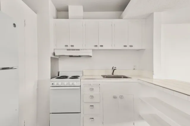 a kitchen with white cabinets and appliances
